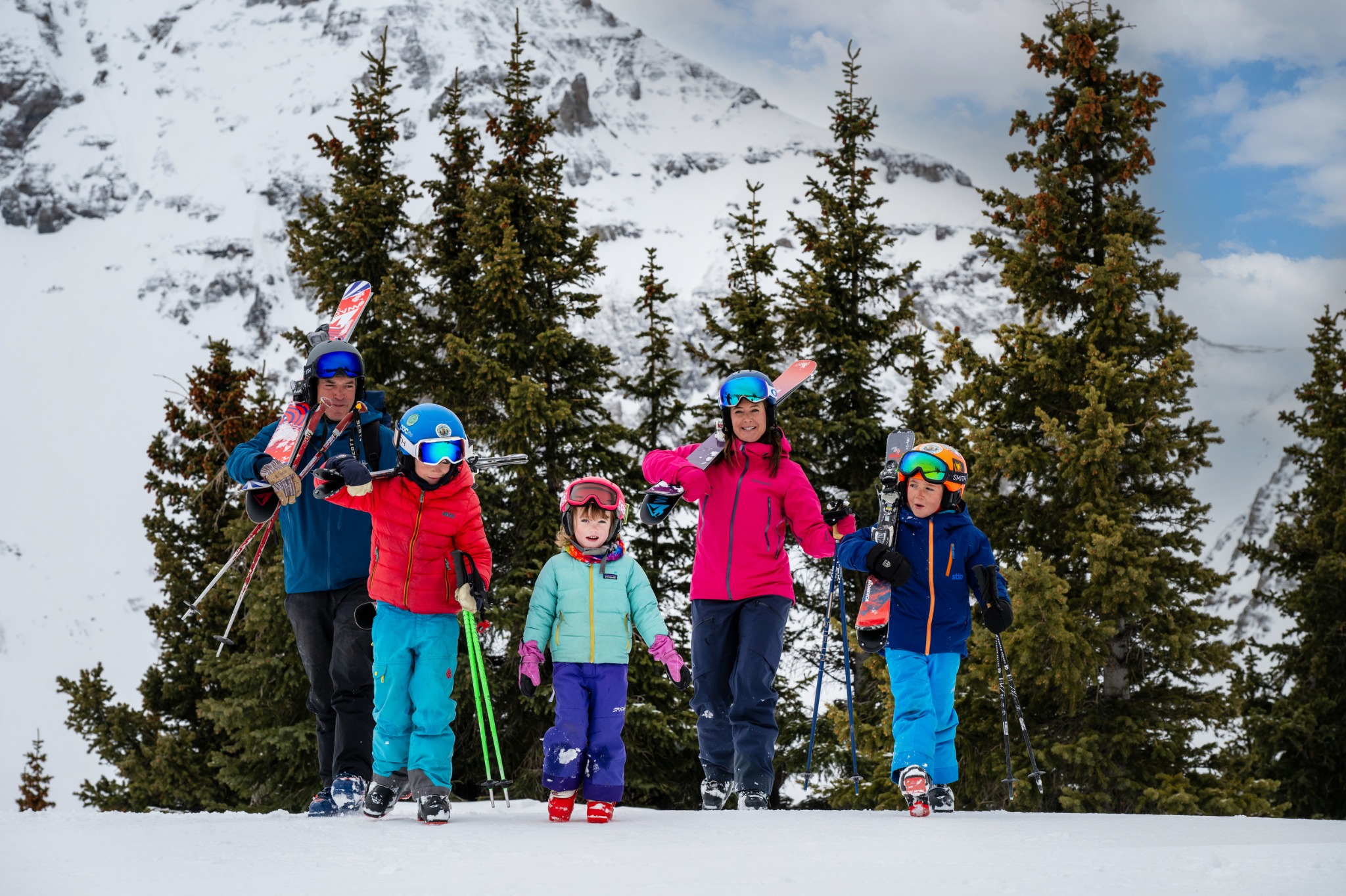 A family carrying their skis together in the mountains