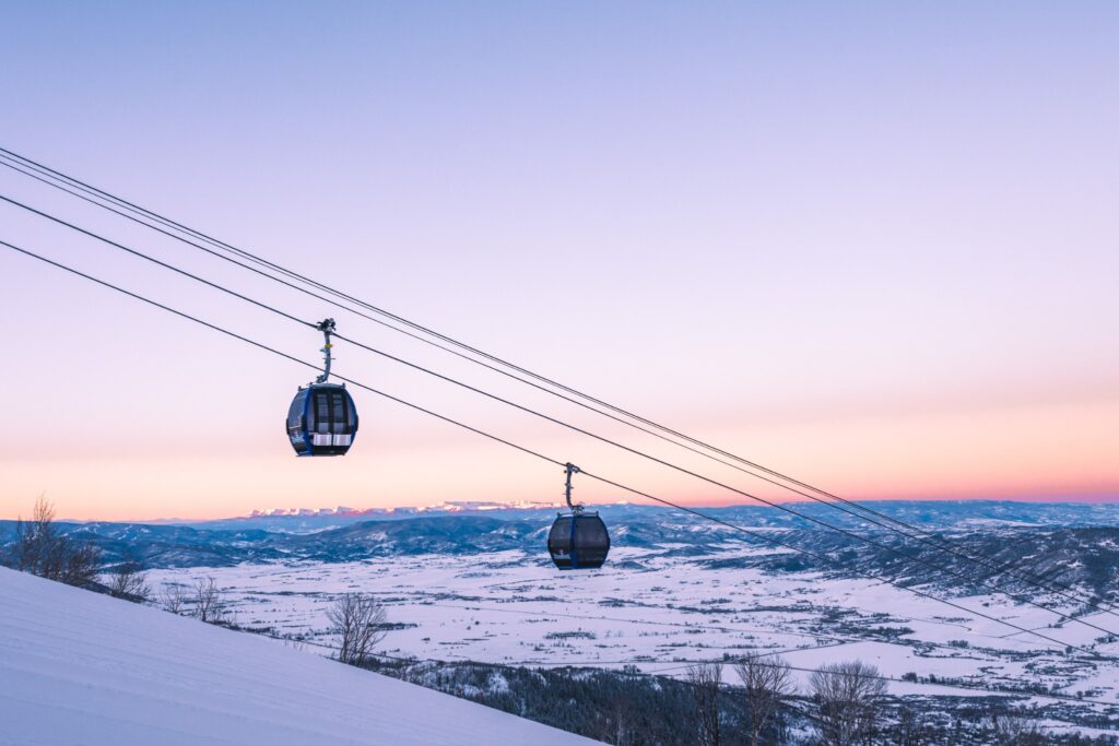 Gondolas crossing a snowy mountain landscape at sunset